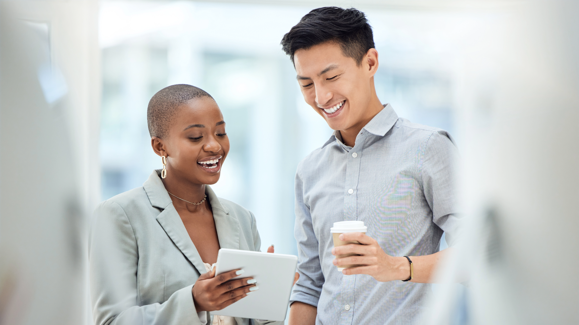 Employees collaborating together in the office, holding a tablet and coffee